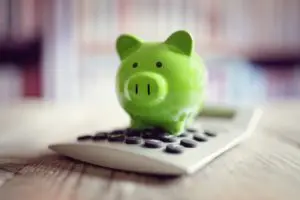 Green piggy bank sitting on top of a calculator