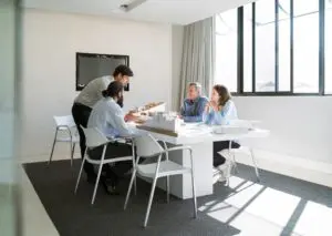 Group of business associates sitting at a table collaborating over paperwork and laptops