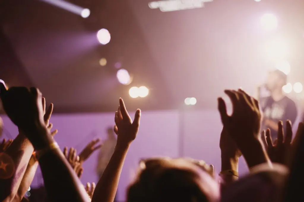 Event attendees at a concert with their hands in the air as a musical artist performs