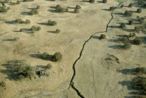 Desert field with large crack from earthquake damage