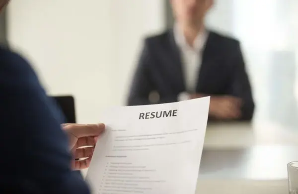 Person holding a resume during a job interview with the interviewer sitting across the desk