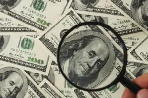 Magnifying glass focusing on Benjamin Franklin's face on a one hundred dollar bill