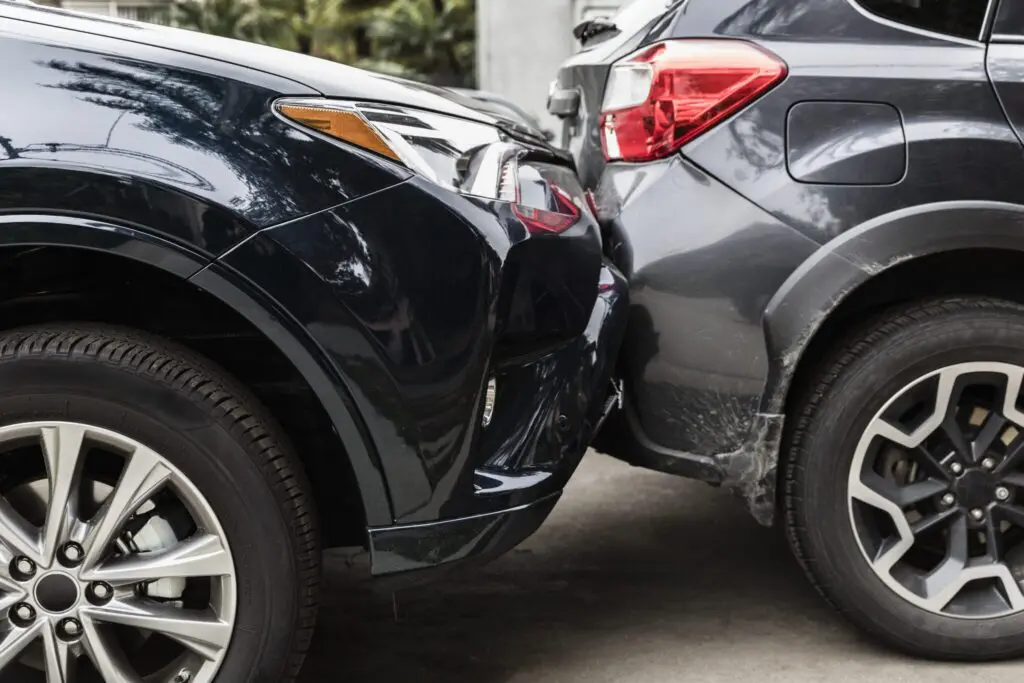 Two cars involved in a rear end collision with visible damage on the back of the gray SUV