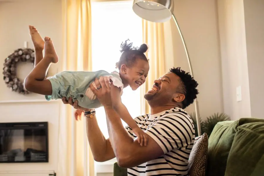 Dad playing with young daughter inside their house