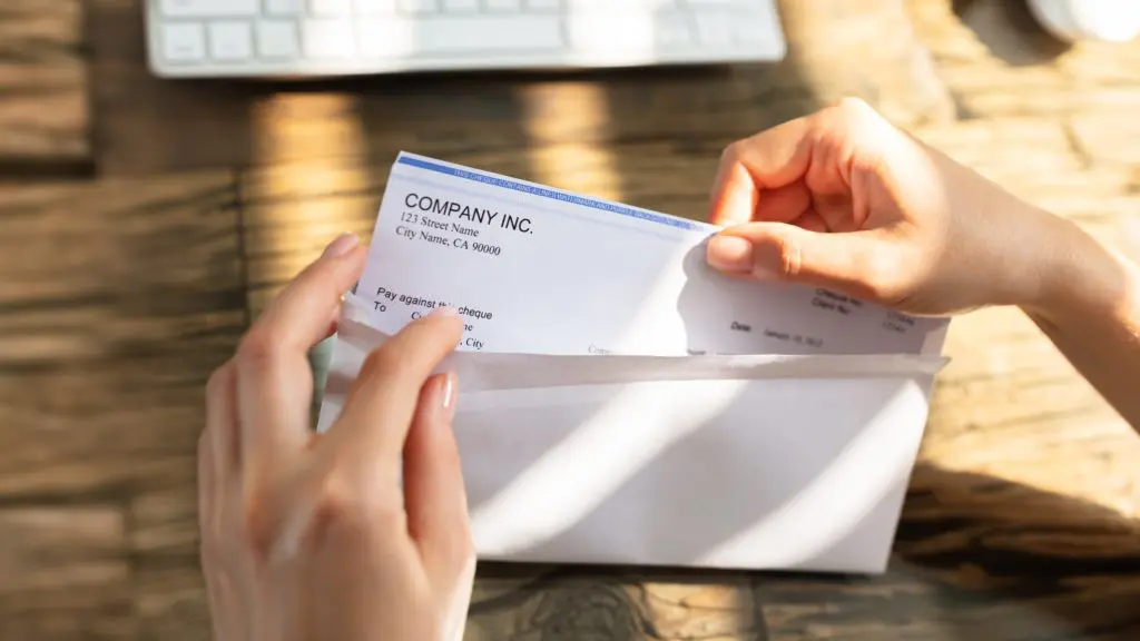 Person taking a paycheck out of an envelope