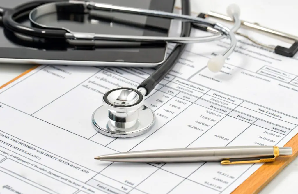 Stethoscope and calculator sitting on a paper with a hospital bill printed on it