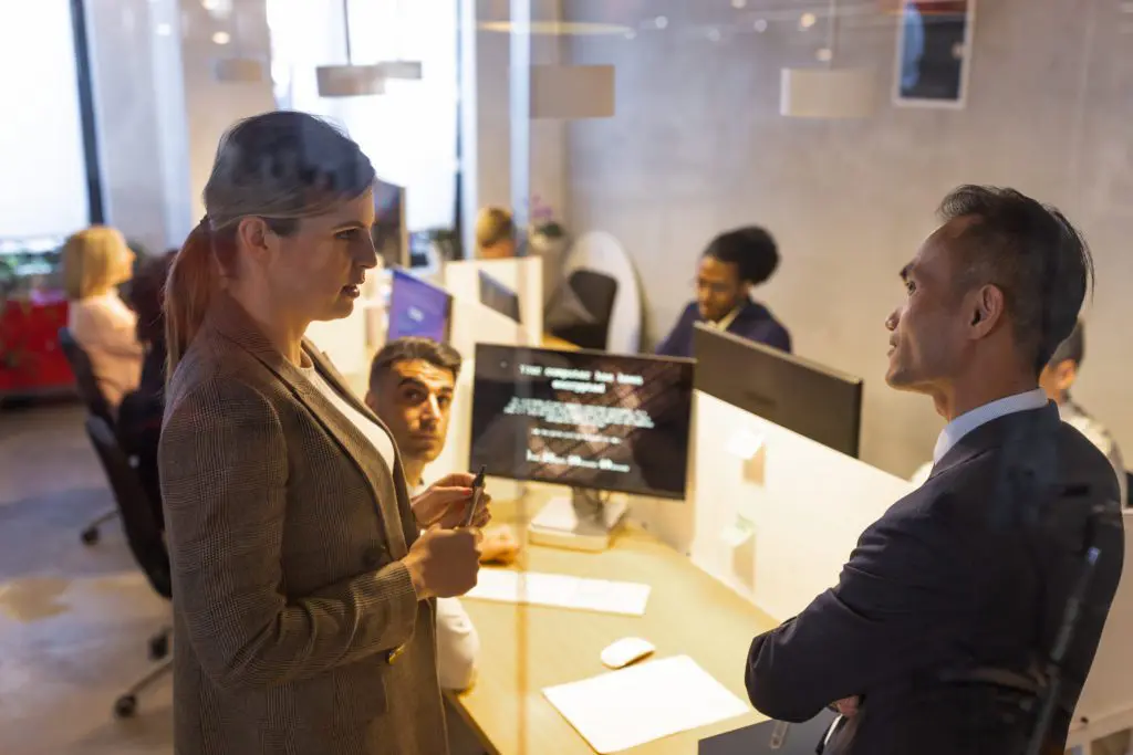Businesswoman and businessman talking inside a conference room with associates