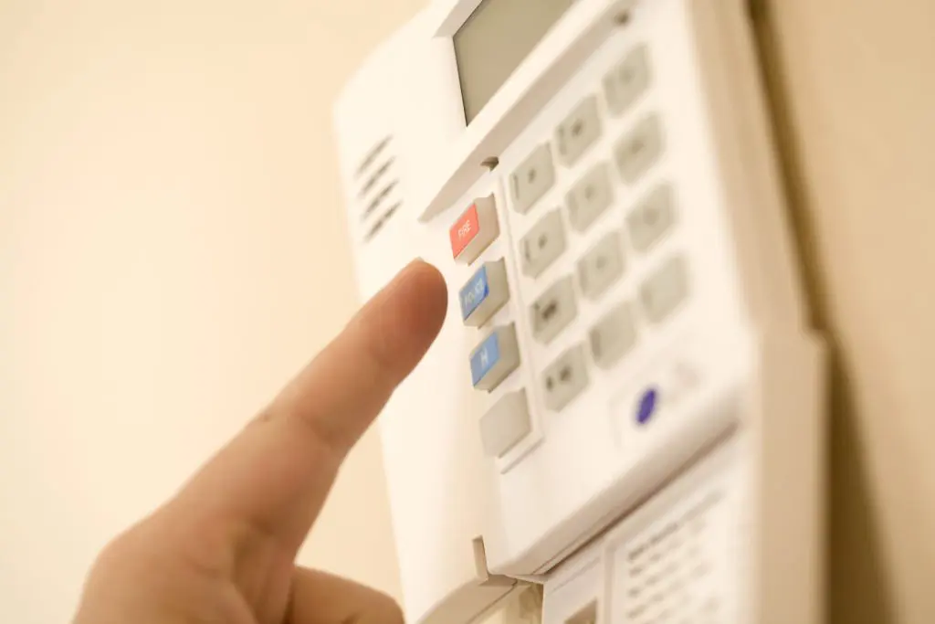 Finger pressing the police call button on a home security system panel