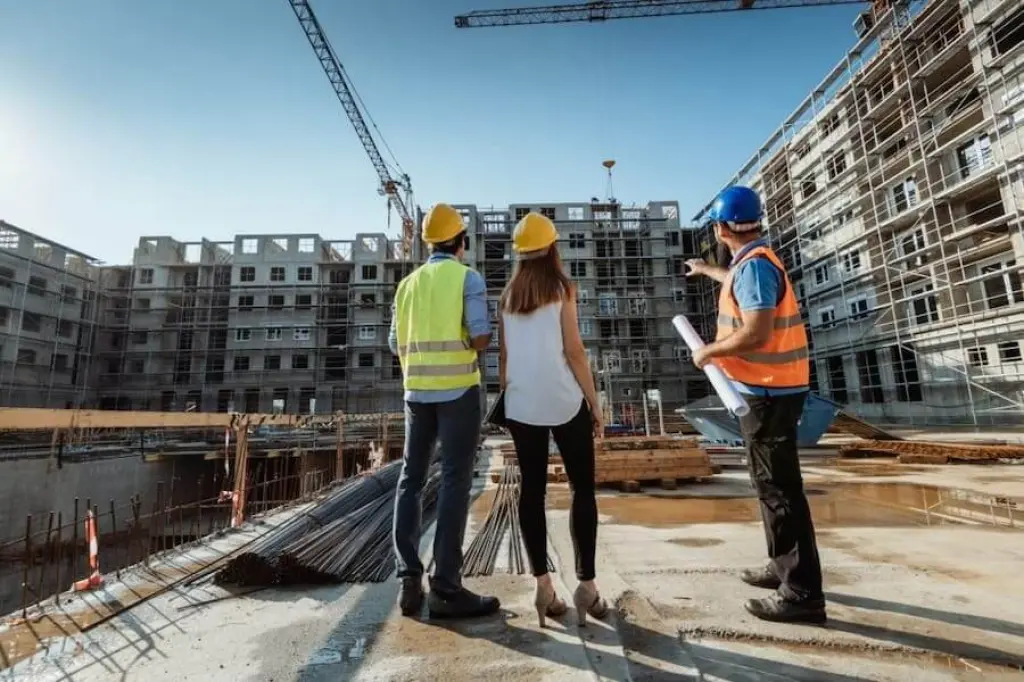 Employees working on construction site, wearing protective equipment and discussing next construction phase