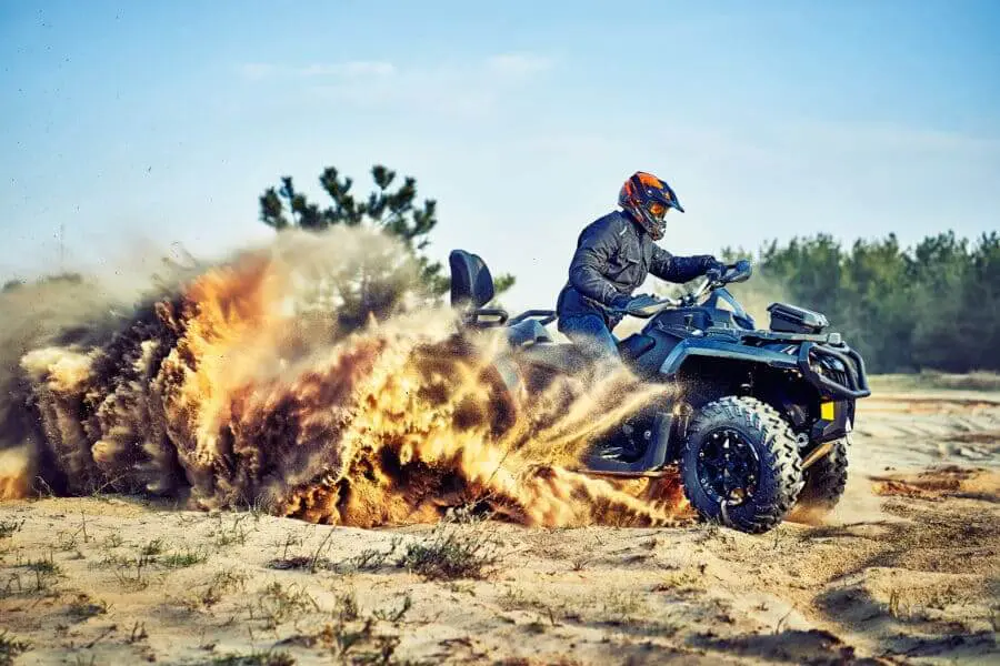 Teen Riding ATV In Sand Dunes Making A Turn In The Sand
