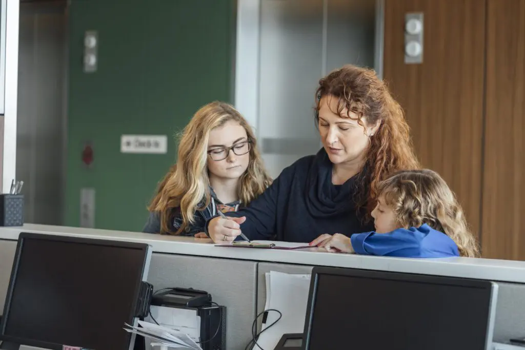Family with two children and mother completing paperwork and checking out at a doctor office