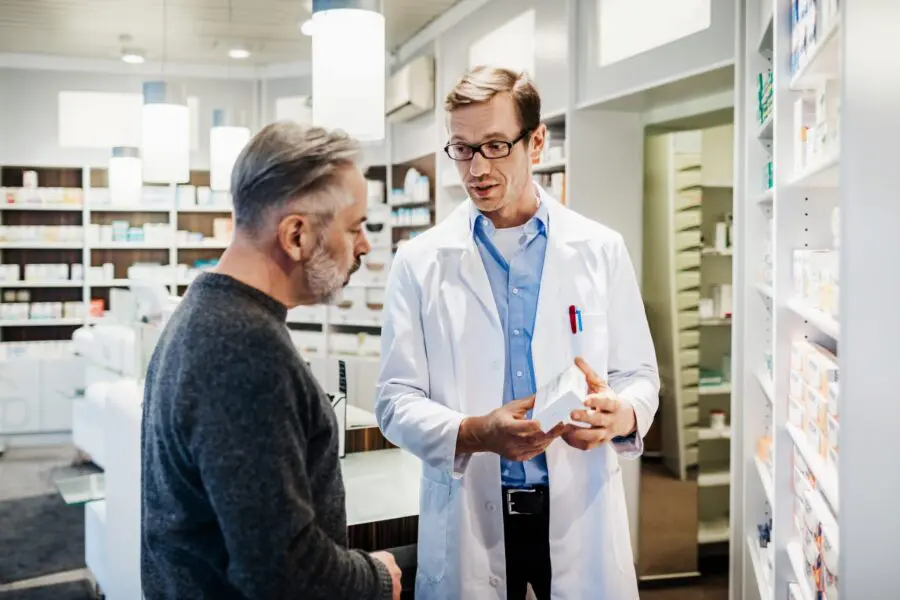 A pharmacist advising a customer on instructions concerning how to take the prescription medicine.