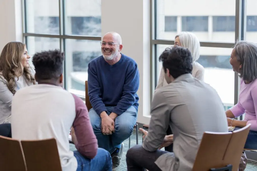 The multi-ethnic community group sit in a circle and brainstorm ideas