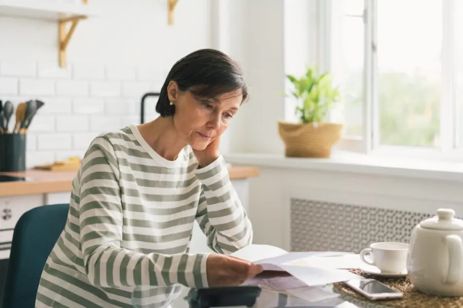 Upset female thinking about high prices while looking at utilities, gas, electricity, rental charges, water bill due to inflation and crisis and no Disability Insurance