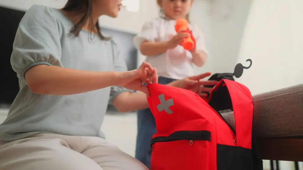 Mother and child packing a flashlight into a first aid backpack