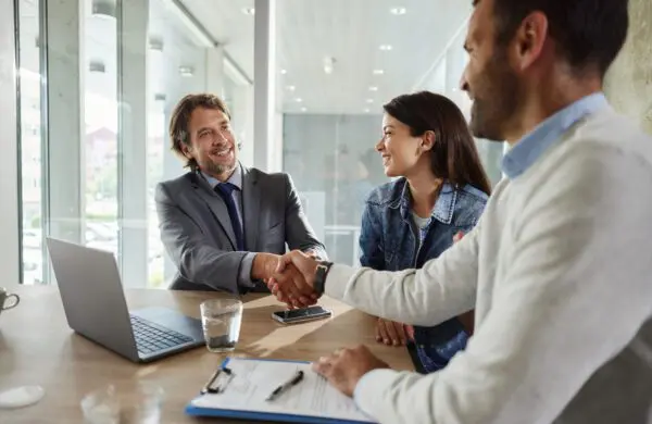 Happy insurance agent came to a successful agreement with a couple on a meeting in the office.