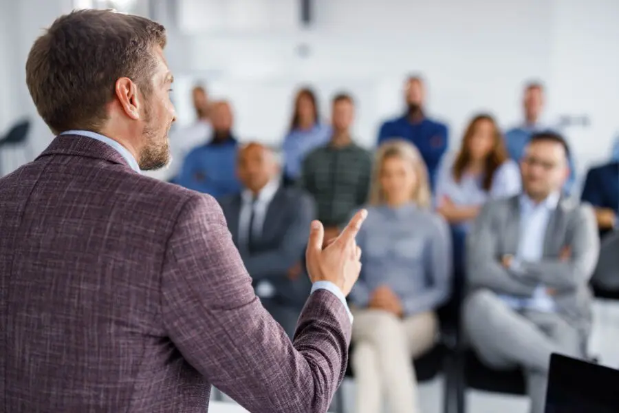 Mid adult CEO giving a speech to his colleagues during an education event in board room.