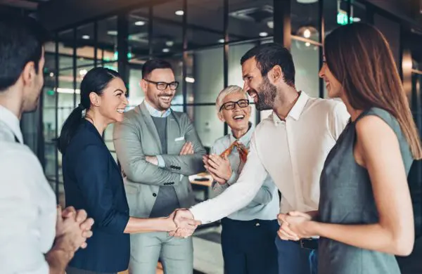Cheerful business team in an office shaking hands and laughing during a successful meeting