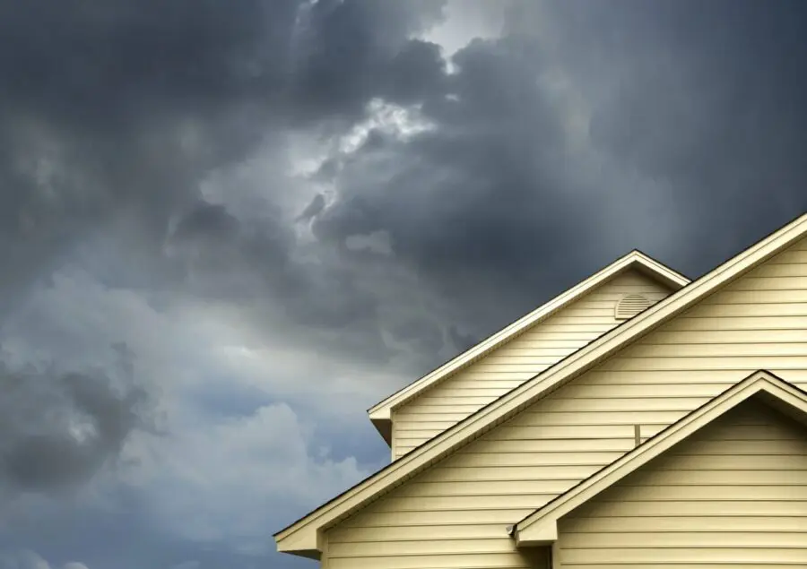 close up shot of yellow siding house over storm clouds.