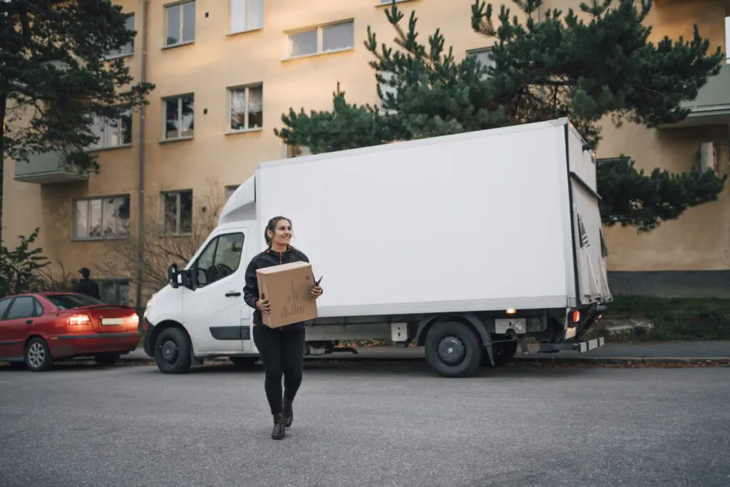 Delivery woman walking away from a van with a box and scanner in her hands