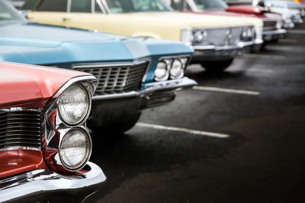 Classic auto vehicles in a row parked on asphalt parking lot participating in a classic car show