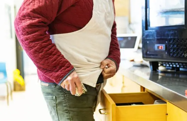 A male employee stealing money from a cash register till