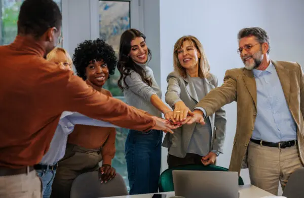 A cheerful multigenerational business team in the office celebrating a successful year with a joint hand stack