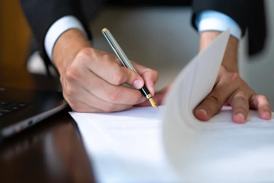 Close-up of hands of unknown businessman in suit signing official document