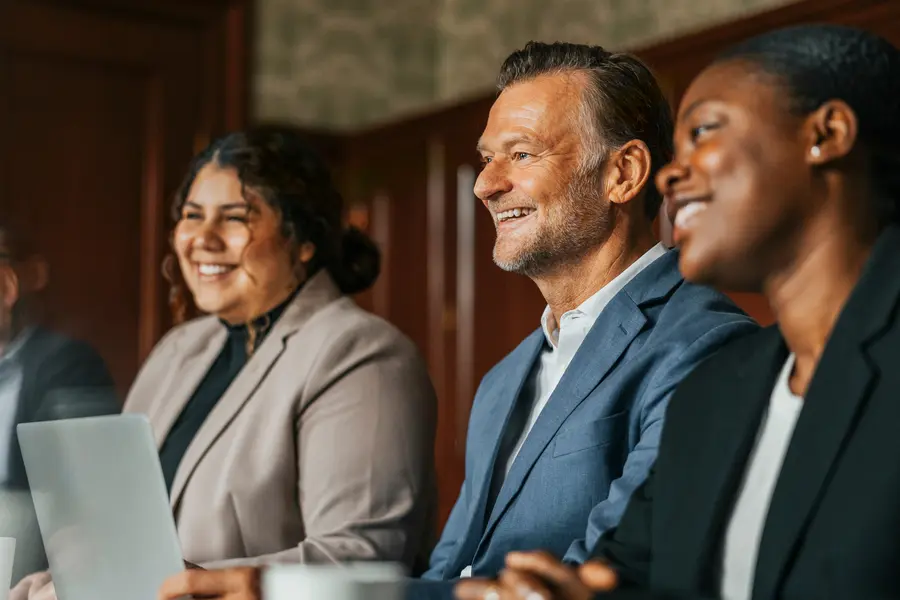 Team of smiling business professionals sitting next to each other during meeting in office board room