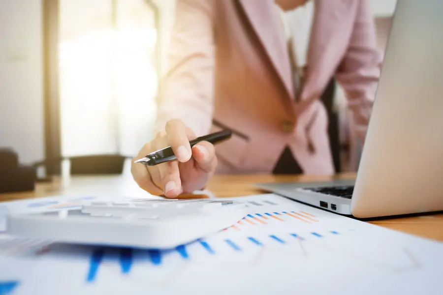 Business woman working in modern office with a laptop, calculator and financial documents