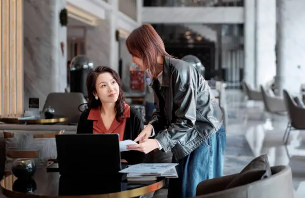 A young intern leans forward while presenting ideas to her supervisor, who listens attentively in a business lounge