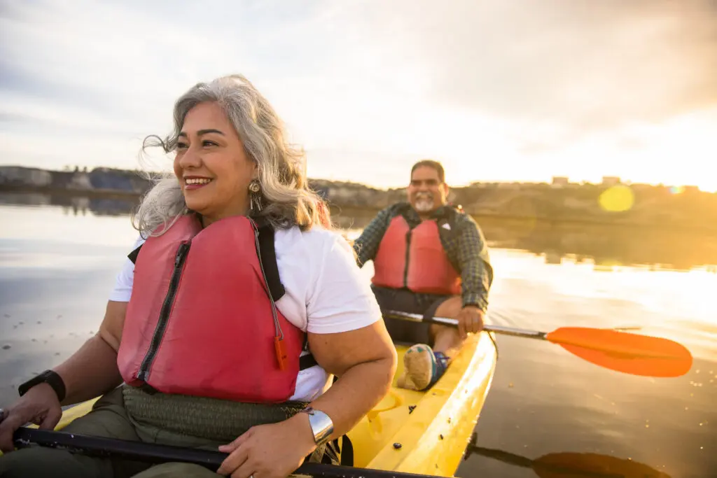 Senior Hispanic couple wearing life jackets kayaking in a body of water