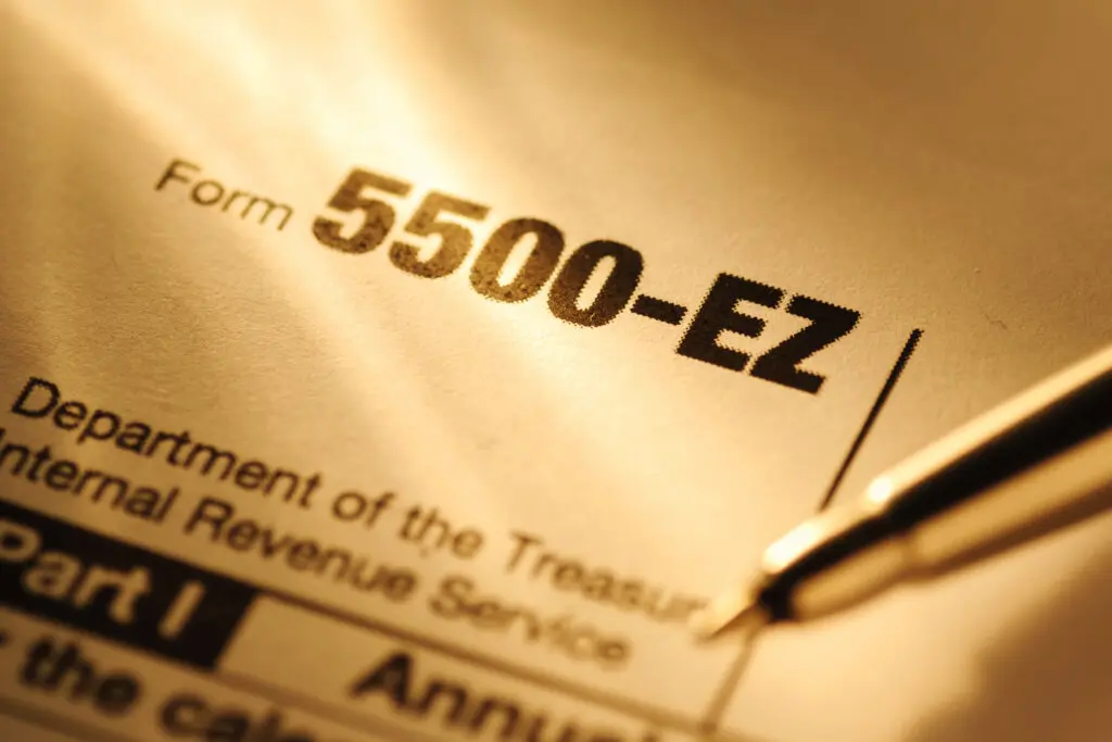 United State IRS form 5500-EZ in close up in sunlight with a pen for completion and submission to the Treasury Department