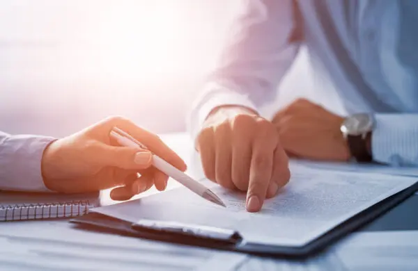 Two business people negotiating and signing a contract at a table in an office