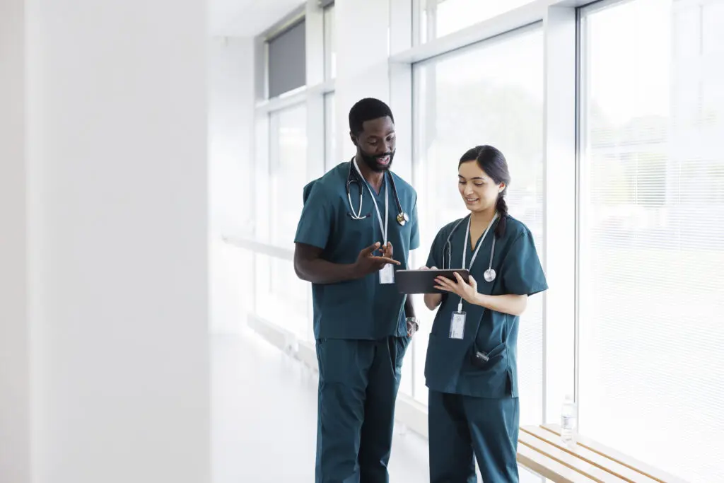 Two doctors in hospital hallway discussing an electronic patient record