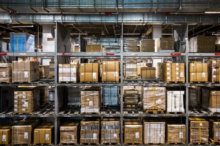A warehouse filled with stacked pallets and boxes organized on industrial shelves