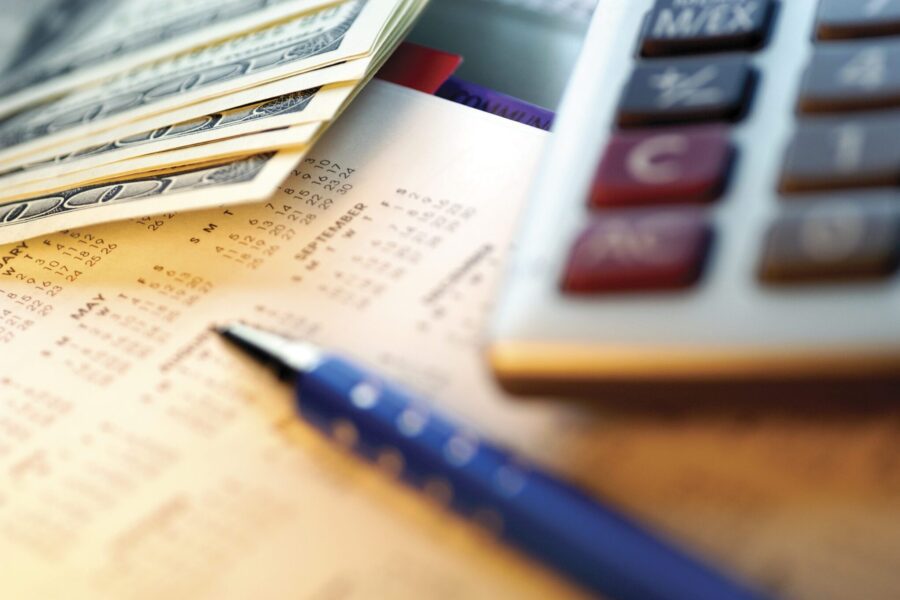 Stacks of cash near a calculator and pan with financial documents