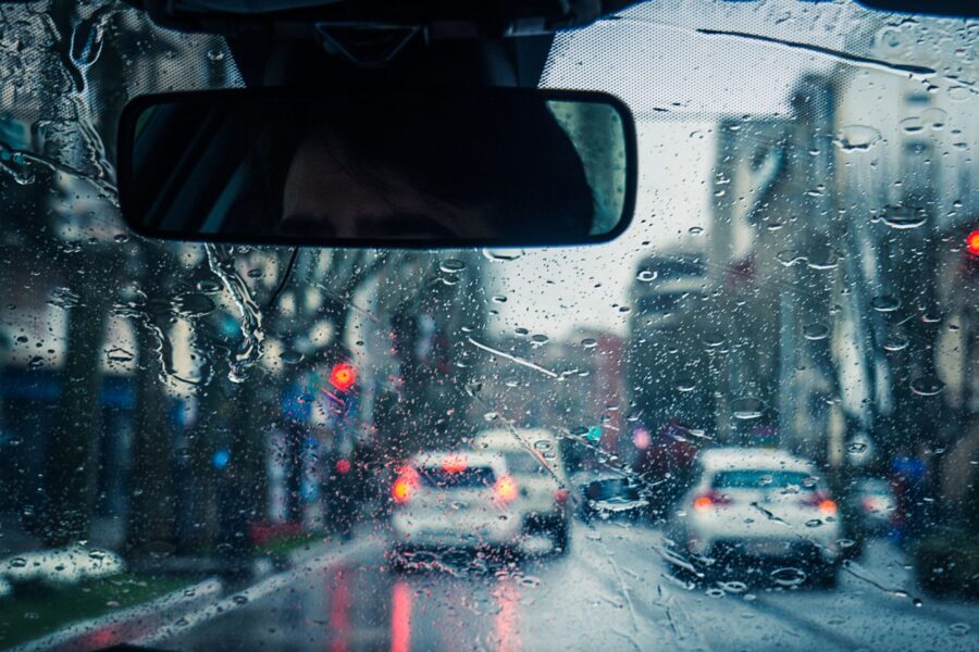 View from inside the car on a rainy day with raindrops on the windshield and light traffic
