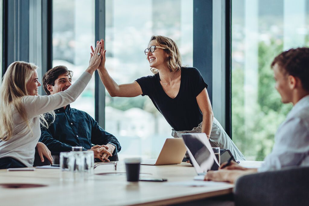 Coworkers giving each other a high five in a meeting