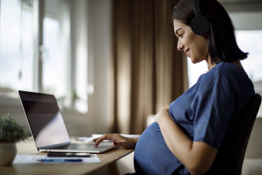 Pregnant Woman With Headphones Using Laptop