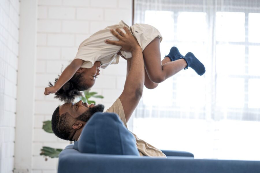 Father Picking Up Daughter In The Air, Face To Face. They Are Having Fun In Weekend At Home.