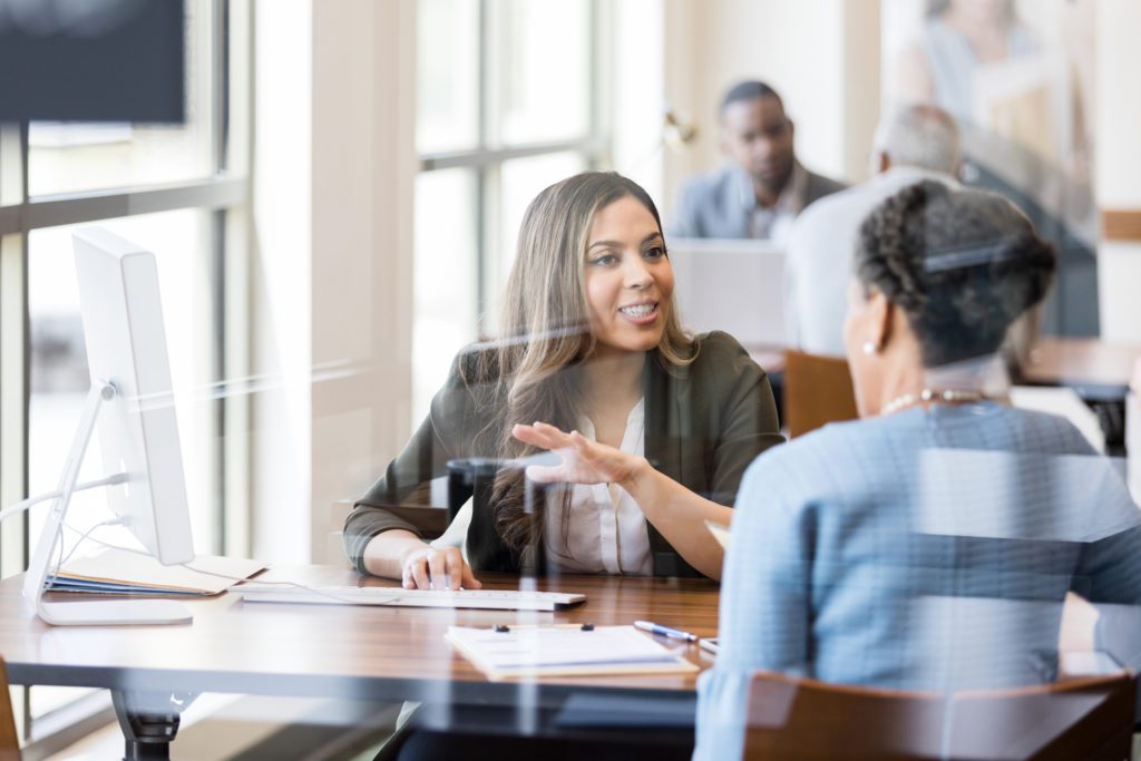 A banker gestures as she explains banking services to a new customer