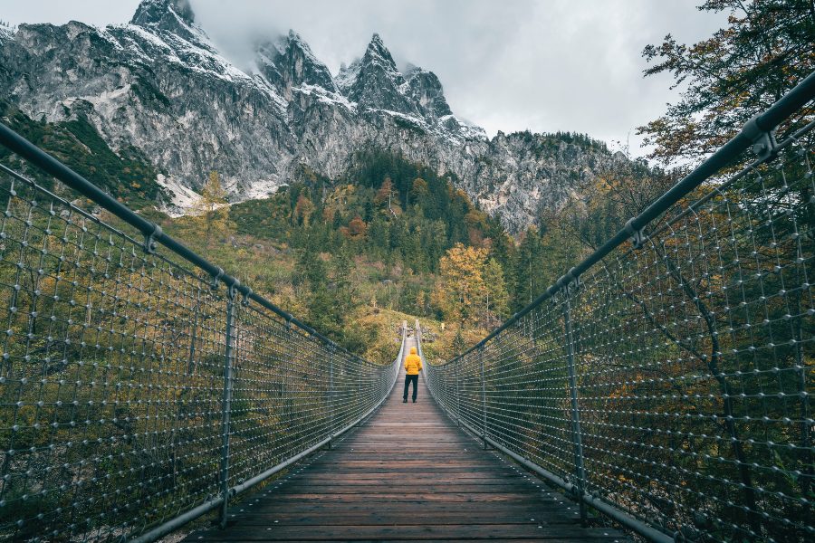 person-walking-across-bridge-in-the-mountains