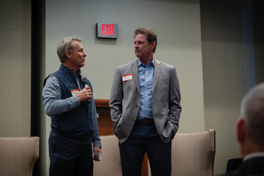 Two businessmen engaging in conversation at a work event while one is holding a microphone