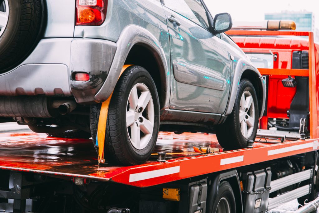 Car being towed by tow truck trailer