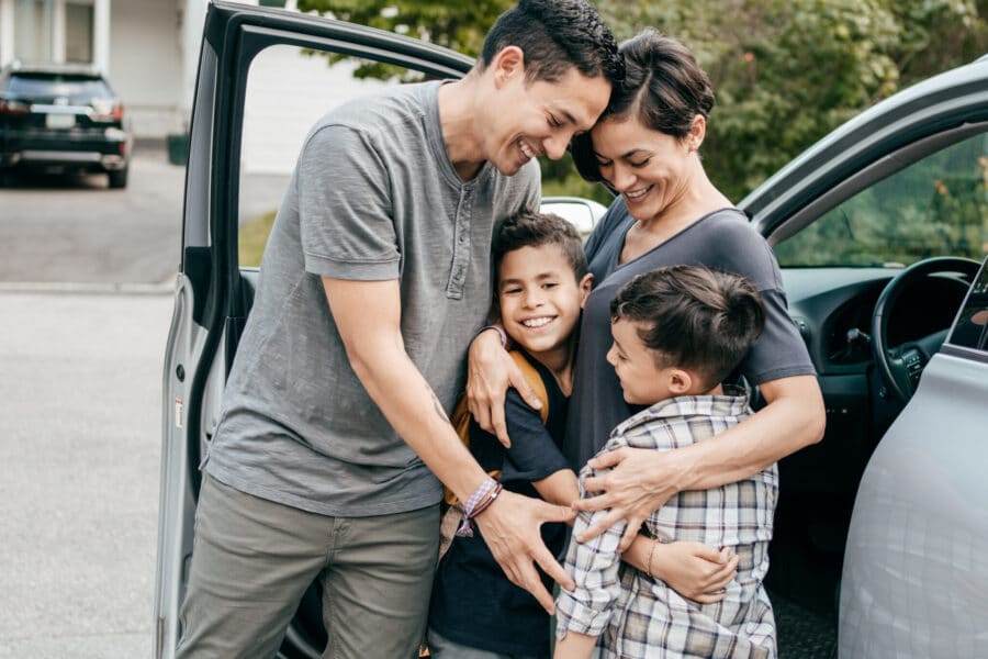 Family With Two Kids . Moment With Hugs Near Car