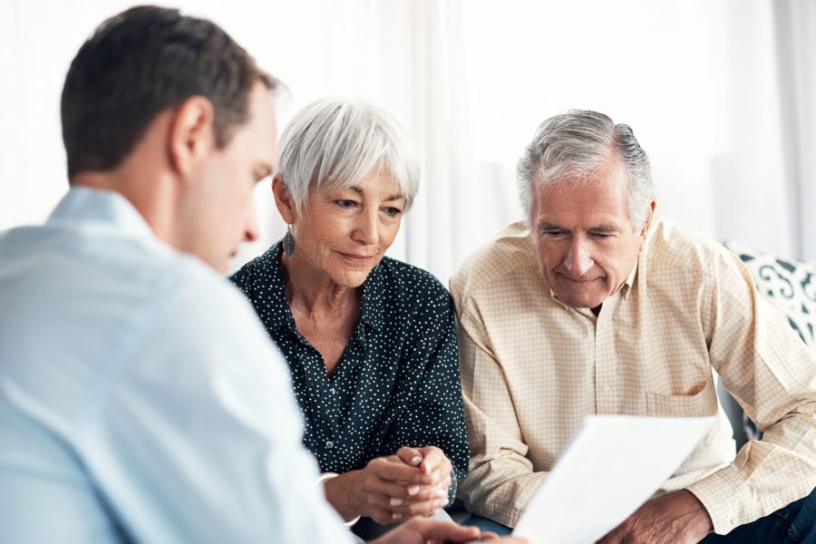 Elderly couple reviewing living trust or will with a financial advisor