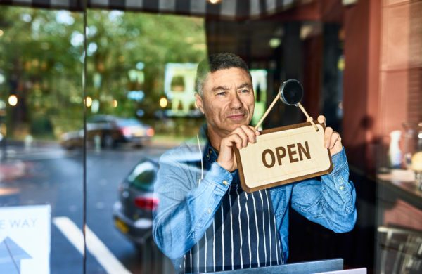 Small business owner placing open sign on window