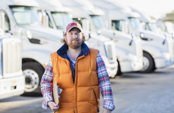 male truck driver in front of semi trucks