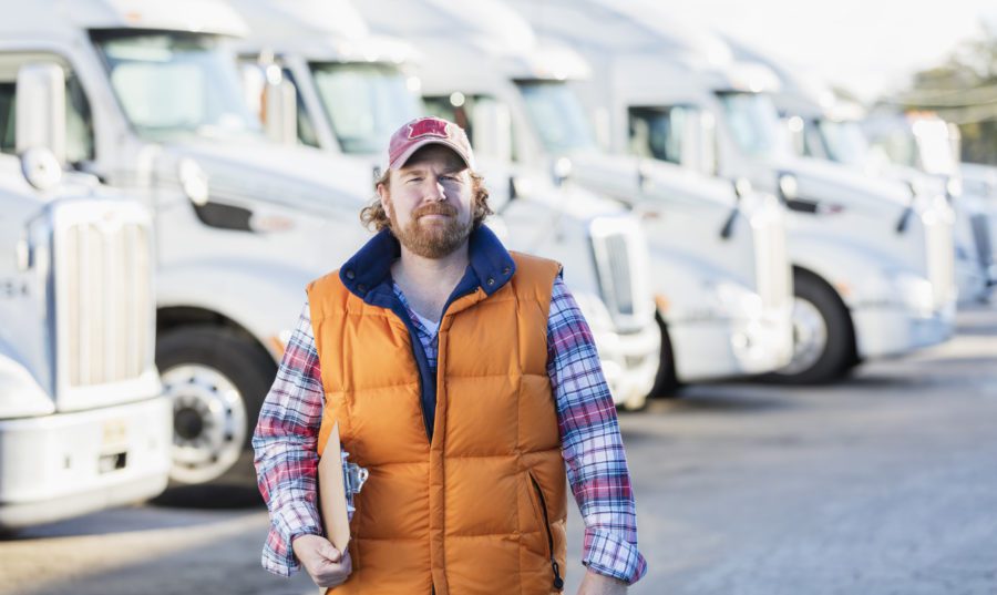 male truck driver in front of semi trucks